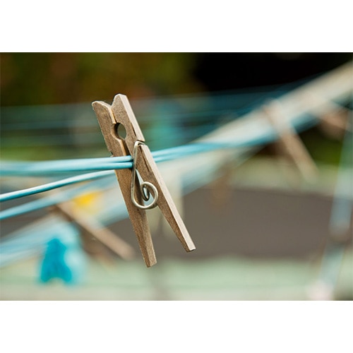 Close-up of wooden peg on blue washing line, blurred background