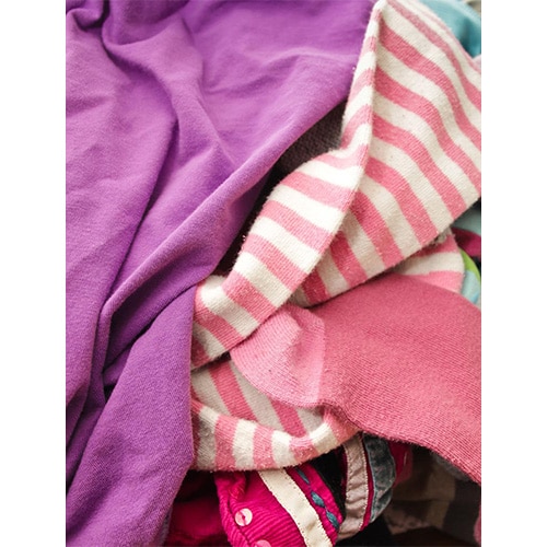 Pile of mixed laundry with purple top, pink sock and pink-white striped jumper